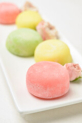 Plate with tasty Japanese mochi and flowers, closeup