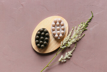 Wooden board with massage soap bars and plant branch on color background