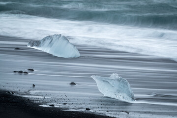 Two small icebergs on Jokulsarlon beach with the sea in the background.