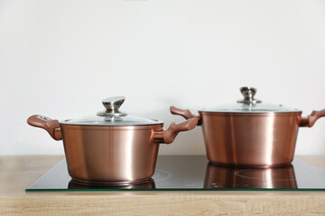 Copper cooking pots on stove near light wall