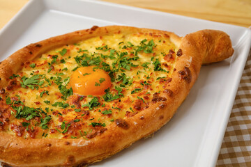 Plate with tasty Ajarian khachapuri on table, closeup