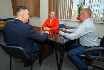 Obraz premium A team of three adult managers sitting at a desk in an office condemning cases