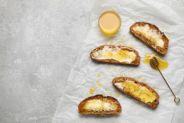 Delicious toasted bread with honey and butter on light background