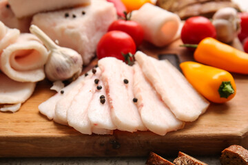 Wooden board with slices of salted lard on table, closeup