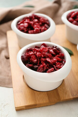 Bowls with tasty dried cranberries on table, closeup