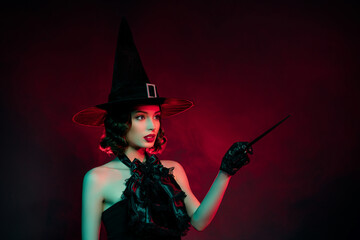 Photo of devil frightening mystic lady wear black dress gothic headwear pointing mafic wand empty space isolated dark red smoke color background - obrazy, fototapety, plakaty