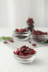 Bowl with tasty dried cranberries on light background, closeup