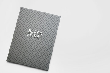 Board with text BLACK FRIDAY on light background