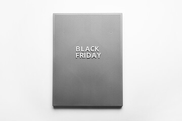 Board with text BLACK FRIDAY on light background
