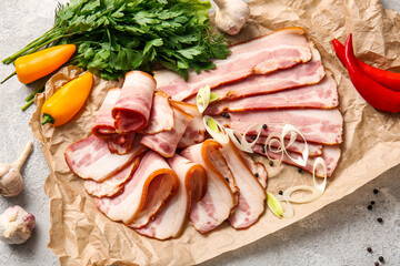 Slices of tasty smoked bacon and fresh vegetables on light background