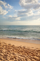 Empty beach with footprints in the sand at sunset.