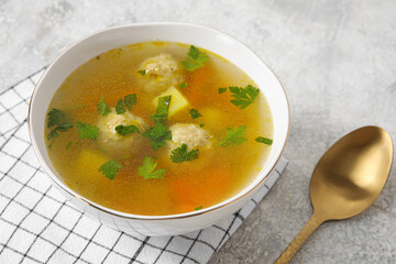Bowl with tasty meatball soup on light background, closeup