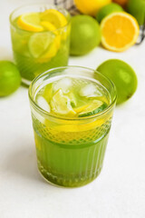 Glasses with tasty green lemonade on light background