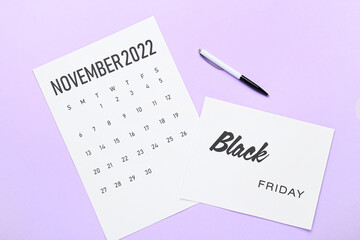 Calendar page of November 2022 and pen on color background. Black Friday