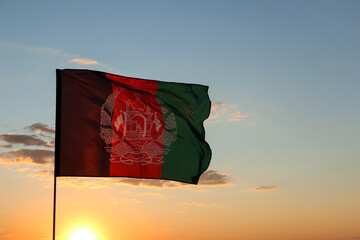 Waving Afghanistan flag against blue sky at sunset