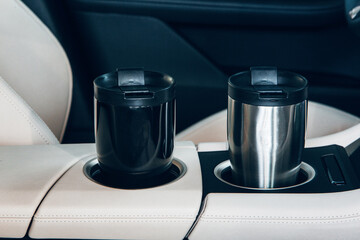 A thermal mug in the cup holder of expensive car