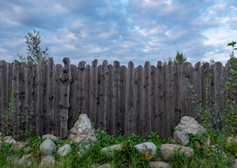 Wooden fence made of planed boards, palisade. An ancient rampart. Fairy gates. Fencing of a house, structure. Wooden gate. Territory protection. Day. Autumn. Russia.