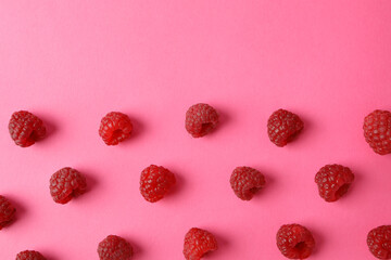 Flat lay composition with red juicy raspberries on a pink background
