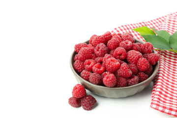Red juicy raspberries in bowl and kitchen towel, isolated on white background