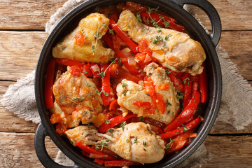 One pot Basque Chicken with Bell Peppers, herbs, tomatoes and onion close up in the pan on the table. Horizontal top view from above