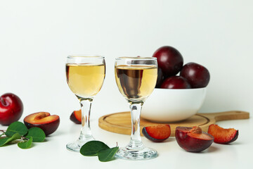 Plum vodka shots and ingredients on white background