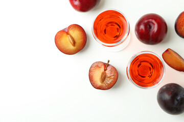 Plum brandy shots and ingredients on white background