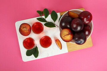 Plum brandy shots and ingredients on pink background