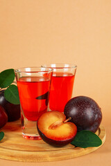 Plum brandy shots and ingredients on beige background