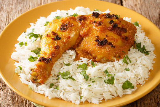 Malaysian Ayam percik or roasted spiced chicken is a grilled chicken dish that is cooked with rich coconut gravy served with rice close up in the plate on the table. Horizontal