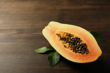 Half of papaya with leaves on wooden background