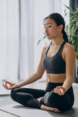 Woman practicing yoga on mat at home