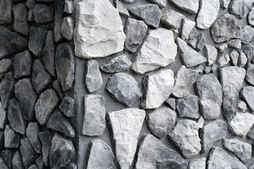 Black and white background of a stone wall.The corner walls are made by hand from concrete and stone, as the decor of a modern building.Background of an ancient stone wall.