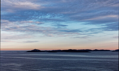 Fototapeta premium Low lying Islands silhouetted in the Early Morning Light on the Norwegian West Coast near to Bergen, on a calm Morning.