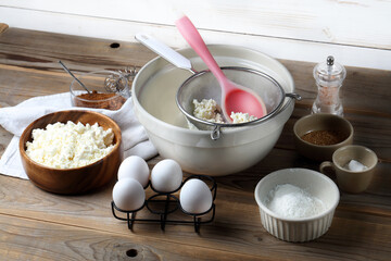 Homemade cheesecake ingredients: cottage cheese, eggs, coconut sugar, salt, corn starch, baking powder and spices on the table
