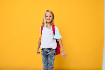 cheerful schoolgirl with a backpack studio yellow background