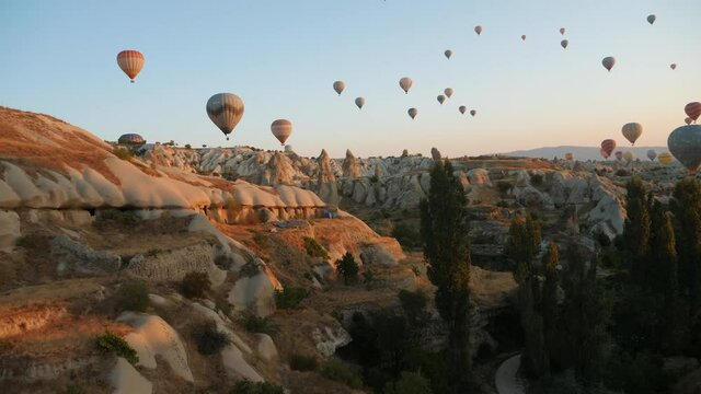 Aerial view, many different hot air balloons fly in the sky over a mountain valley in Cappadocia, Turkey