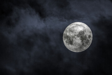Shot of the full moon with clouds on black sky