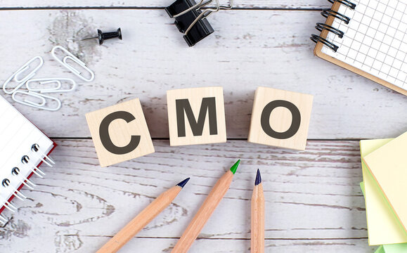 CMO text on wooden block with office tools on the wooden background