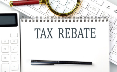 TAX REBATE . Text on notepad with calculator and keyboard,business concept