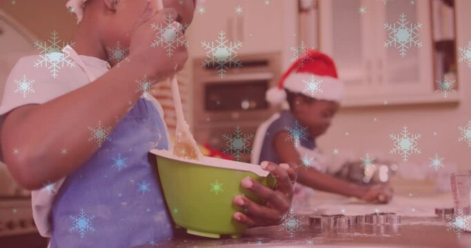 Animation of snow falling over two smiling children with santa hats preparing cookies