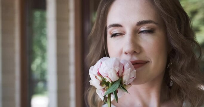 Beautiful romantic woman smells flower peony, portrait of gentle tender lady. Fashionable model posing to camera with flower bud