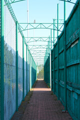 Obraz premium pedestrian walkway fenced with a wooden fence on one side and an iron mesh on the other