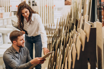 Young man with sales woman choosing tiles at building market