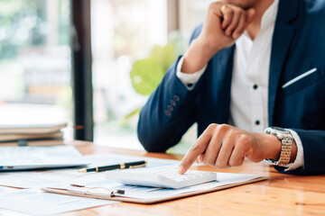 Business man or accountant working on calculator to calculate business data concept. Accounting,investment advisor consulting situation on the financial report and planning a marketing plan at home