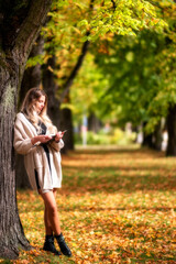 Stylish girl reading book in colorful autumn park