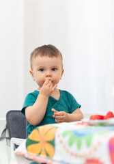 Baby girl eating herself bread while is look at the camera. Baby led weaning method. 