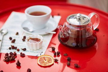 Hot tea in glass teapot and cup, on red background