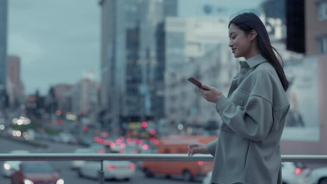 Korean woman using cell phone while walking outdoors