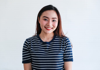 Studio portrait close up shot of Asian young happy beautiful pretty charming cheerful joyful long hair female model wears stripe casual clothing smiling show teeth look at camera on white background