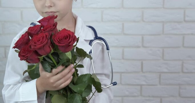 Child bouquet for doctor. A young doctor look at a nice bouquet of roses for doctor day celebration.
